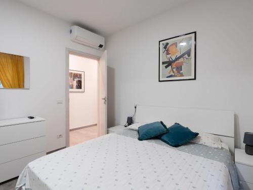 a white bedroom with a bed with two blue pillows at Apartment Balin by Interhome in Diano Castello