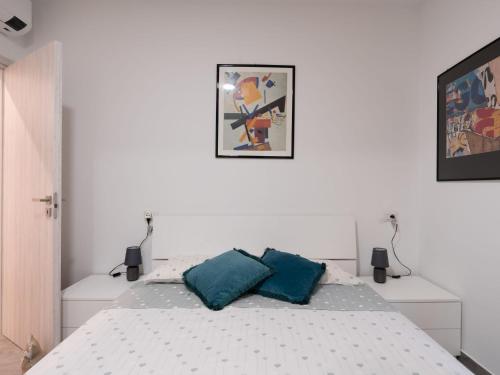 a white bedroom with a bed with two blue pillows at Apartment Balin by Interhome in Diano Castello