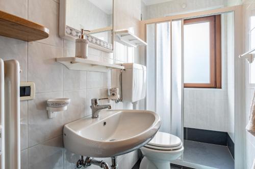a bathroom with a sink and a toilet and a window at Appartamento Vioz in Peio