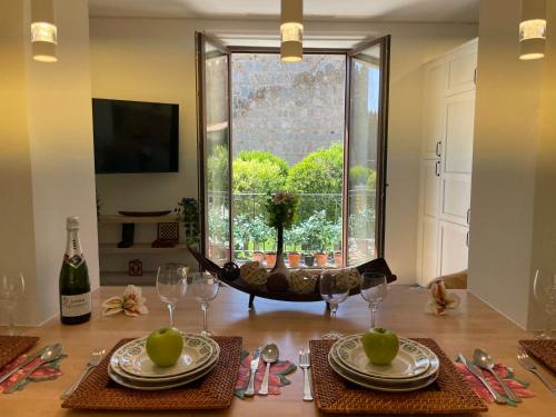 a dining room table with plates and glasses and a window at El balcón de la Muralla in Ávila