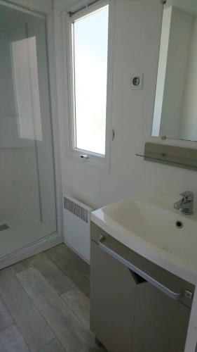 une salle de bain blanche avec un lavabo et une fenêtre dans l'établissement 45mn de Paris - Beau mobilhome pour famille et travail, à Saint-Chéron
