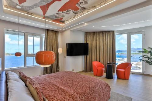 a living room with a couch and a tv and windows at Serenity Penthouse - The Pinnacle of Luxury in Maho Reef