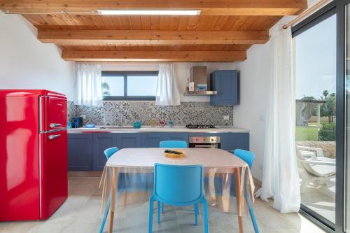 a kitchen with a table with blue chairs and a red refrigerator at Agrivillage San Lorenzo in San Lorenzo