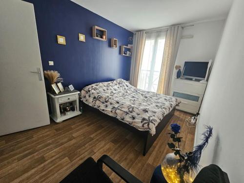 une chambre avec un lit et un mur bleu dans l'établissement Appart entier 55m 2p et Parking, à Versailles