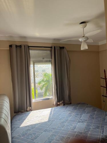 um quarto com uma cama e uma janela em Lindo apto 3 qtos, a 350 mtrs praia da enseada com serviço de praia e portaria 24 hrs próx casa grande hotel, hipermercados, farmácias bancos no Guarujá