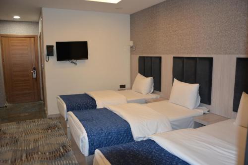 a hotel room with three beds and a flat screen tv at MyFlower 3 Hotel in Erbil