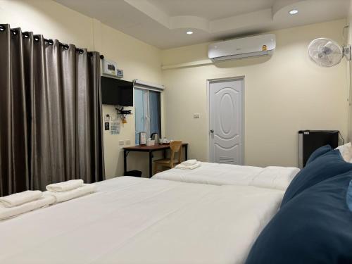 two white beds in a room with a window at Mangoes Pattaya in Na Jomtien