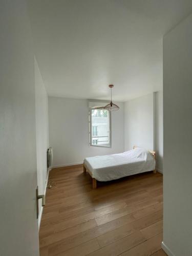 une chambre blanche avec un lit et une fenêtre dans l'établissement Appartement avec vue sur le Stade de France & le canal, à Saint-Denis