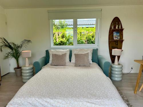 a bedroom with a bed with two lamps and a window at NEW - The Surf Shack - on a lake near Amsterdam! in Vinkeveen