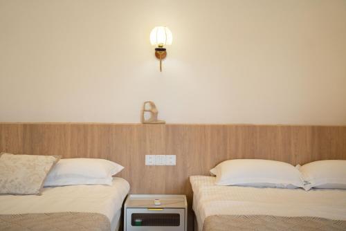 two beds sitting next to each other in a room at Shanghai Yi Du B&B - Near Nanjing West Road commercial district, 350 walk from the Natural History Museum subway in Shanghai