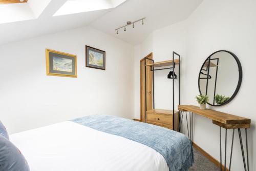 a white bedroom with a bed and a mirror at Host & Stay - Crackin' View in Hexham