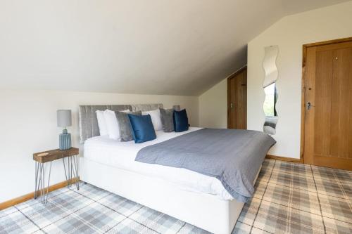 a bedroom with a large white bed with blue pillows at Host & Stay - Crackin' View in Hexham