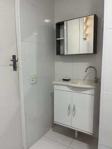 um banheiro branco com uma pia e um espelho em Lindo apto 3 qtos, a 350 mtrs praia da enseada com serviço de praia e portaria 24 hrs próx casa grande hotel, hipermercados, farmácias bancos no Guarujá