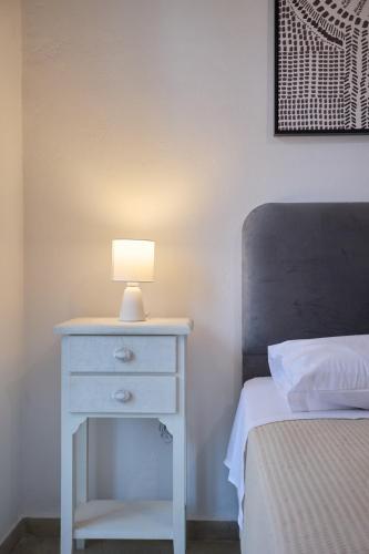 a white nightstand with a lamp on it next to a bed at Chios Downtown Apartments in Chios