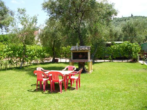 a group of red chairs around a table in a yard at Olga's Garden Apartments in Almiros Beach