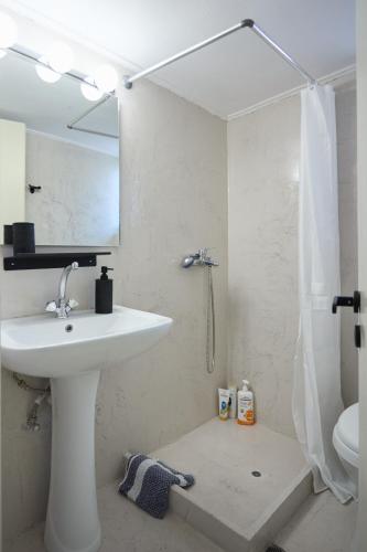 a white bathroom with a sink and a shower at Chios Downtown Apartments in Chios