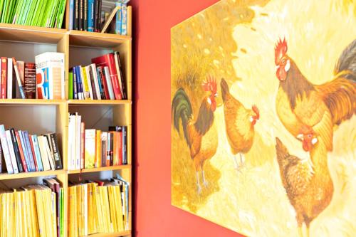 a painting of roosters is next to a book shelf at Austernfischer Haus in Pellworm