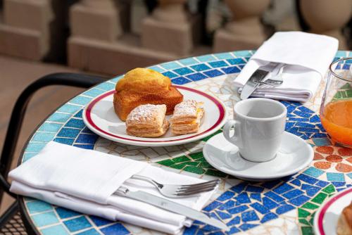 a table with a plate of pastries and a cup of coffee at Phi Hotel Canalgrande in Modena