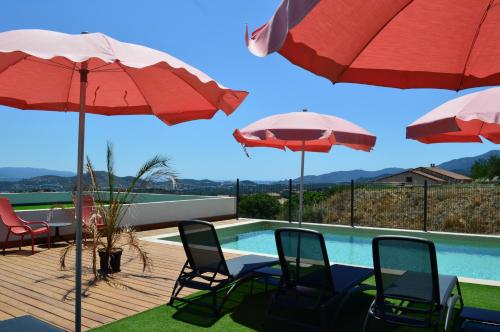 a patio with chairs and umbrellas and a swimming pool at Hôtel Casa Matteu in Afa