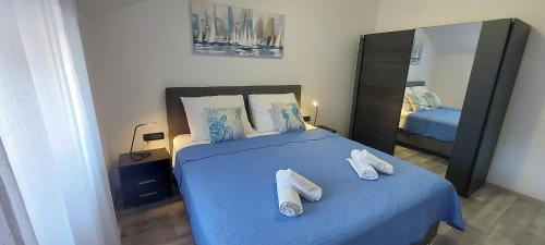 a bedroom with a bed with blue sheets and a mirror at Villa Irene in Veli Lošinj