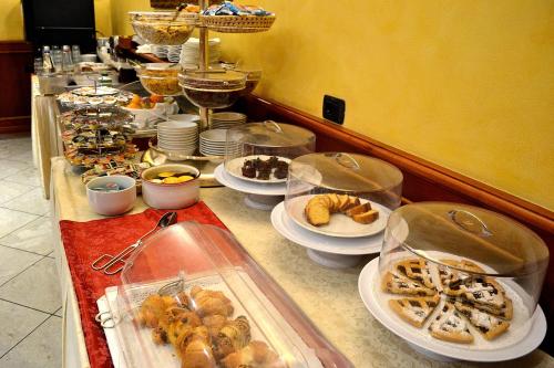 a buffet line with plates of food and desserts at Tricolore Hotel in Gaida