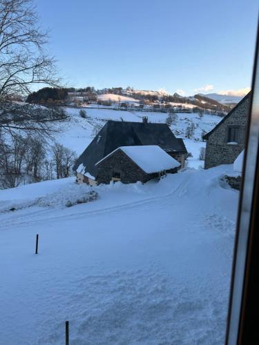 une vieille maison sous la neige avec un sol recouvert de neige dans l'établissement Jo et lo location, à Chastreix