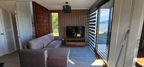 a living room with a couch and a television at Cabaña 1 Lican Ray primera linea in Licán Ray
