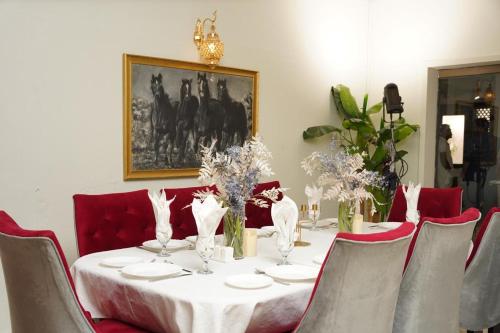 a dining room table with a white tablecloth and red chairs at Grace Boutique Hotel in Islamabad
