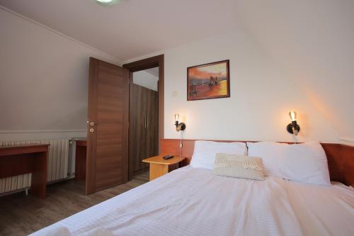 a bedroom with a white bed with a wooden headboard at Vila sa Bazenom, Horizont in Goč