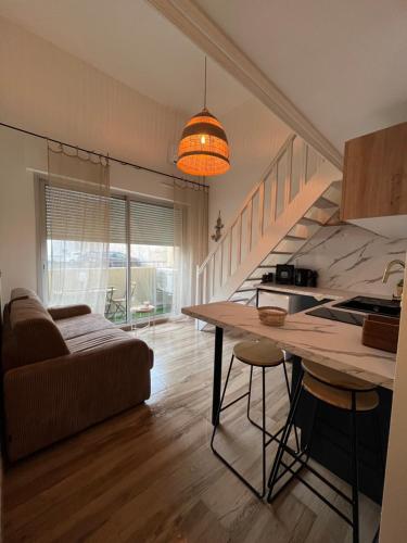 Il comprend une cuisine et un salon avec une table et des escaliers. dans l'établissement Duplex Climatisé Cadre Royal, à Sète