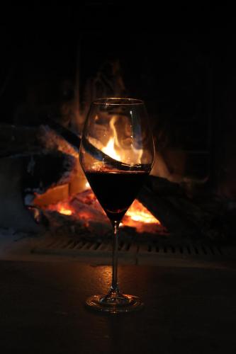 a glass of wine sitting in front of a fire at Dimore Di Charme Lago Matese in San Gregorio