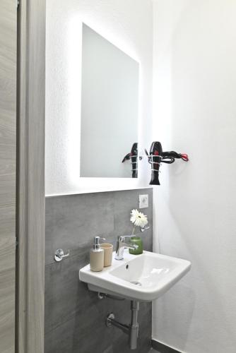 a bathroom with a white sink and a mirror at IzzHome The Breeze in Cagliari