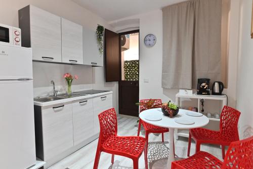 a kitchen with red chairs and a white table at IzzHome The Breeze in Cagliari