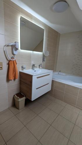 a bathroom with a sink and a tub and a mirror at Apartmán Štěpánka in Ratíškovice
