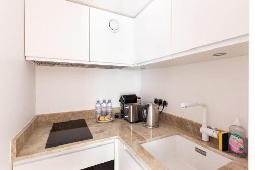 une cuisine avec des armoires blanches et un évier dans l'établissement Musée d'Orsay-Saint Germain-Invalides-Famille, à Paris