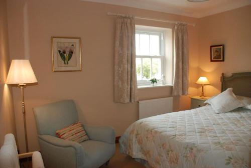 a bedroom with a bed and a chair and a window at Rose Cottage, Chipping Campden in Chipping Campden