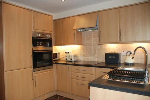 a kitchen with wooden cabinets and black counter tops at Rose Cottage, Chipping Campden in Chipping Campden