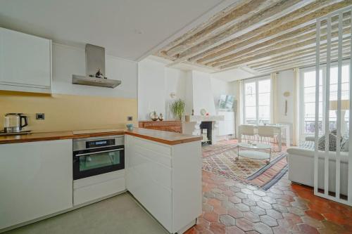 une cuisine avec des armoires blanches et un salon dans l'établissement 2 BR with the Best Location of Paris in 2nd Arr, à Paris