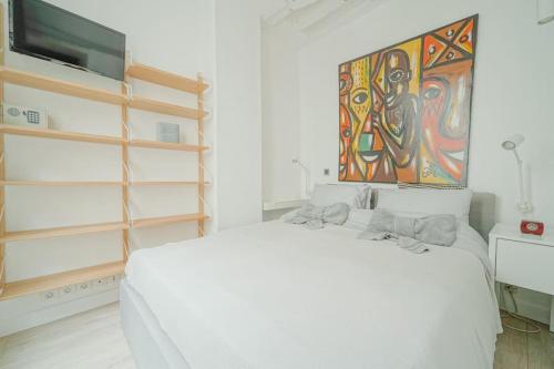 une chambre avec un lit blanc et un tableau au mur dans l'établissement 2 BR with the Best Location of Paris in 2nd Arr, à Paris