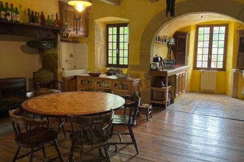 une cuisine avec une table et des chaises dans une pièce dans l'établissement Gite à la campagne - Rouergue-Lot-Aveyron, à Naussac