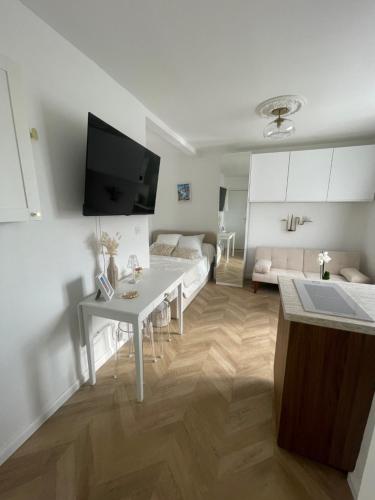 un salon blanc avec une table blanche et un canapé dans l'établissement Charmant studio perché sur les toits, avec ascenseur, 16 ème quartier calme securise- Proche quai Seine, à Paris