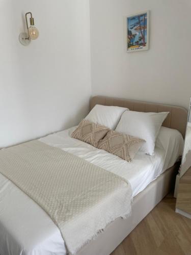 un lit blanc avec des draps et des oreillers blancs dans l'établissement Charmant studio perché sur les toits, avec ascenseur, 16 ème quartier calme securise- Proche quai Seine, à Paris