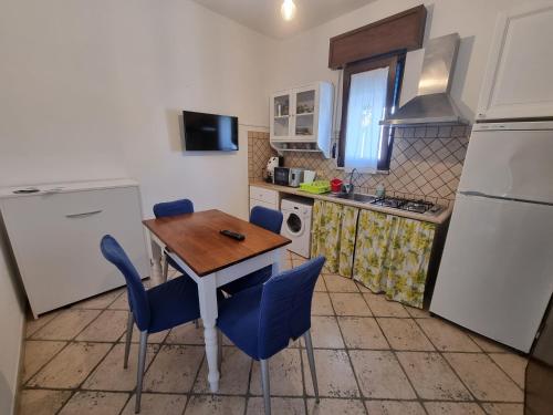 a small kitchen with a wooden table and blue chairs at Salento holiday house in Torchiarolo