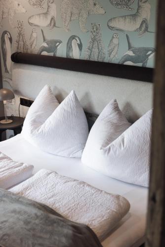 a bed with white sheets and pillows on it at Zellrooms in Zell am Ziller