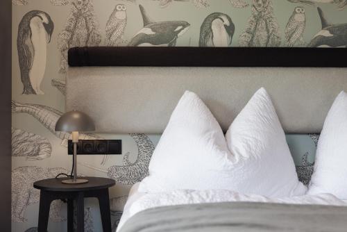 a bed with white pillows and a lamp on a table at Zellrooms in Zell am Ziller