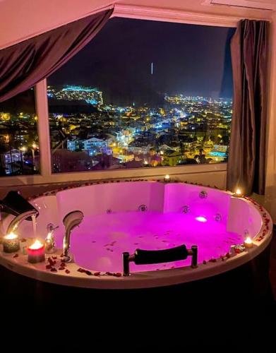 un bagno con una vasca da bagno viola davanti a una finestra di Luna House - Manzara, jakuzi, 4 yatak odası a Fethiye