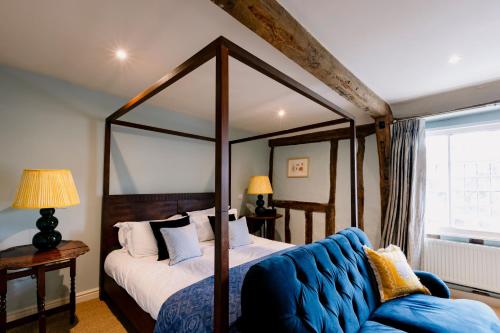a bedroom with a canopy bed and a blue couch at The Crown, Bildeston in Bildeston