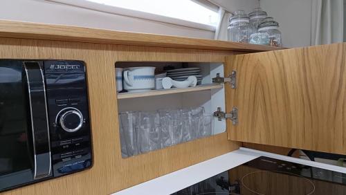 a kitchen with a cupboard with glasses and a microwave at Sunset River in Figueira da Foz