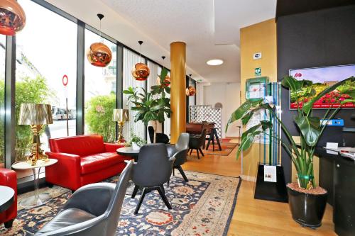 a lobby with a red couch and a table and chairs at Hôtel Hor Europe in Paris
