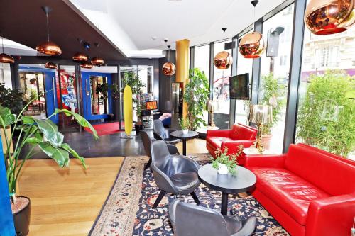 a lobby with a red couch and chairs and tables at Hôtel Hor Europe in Paris